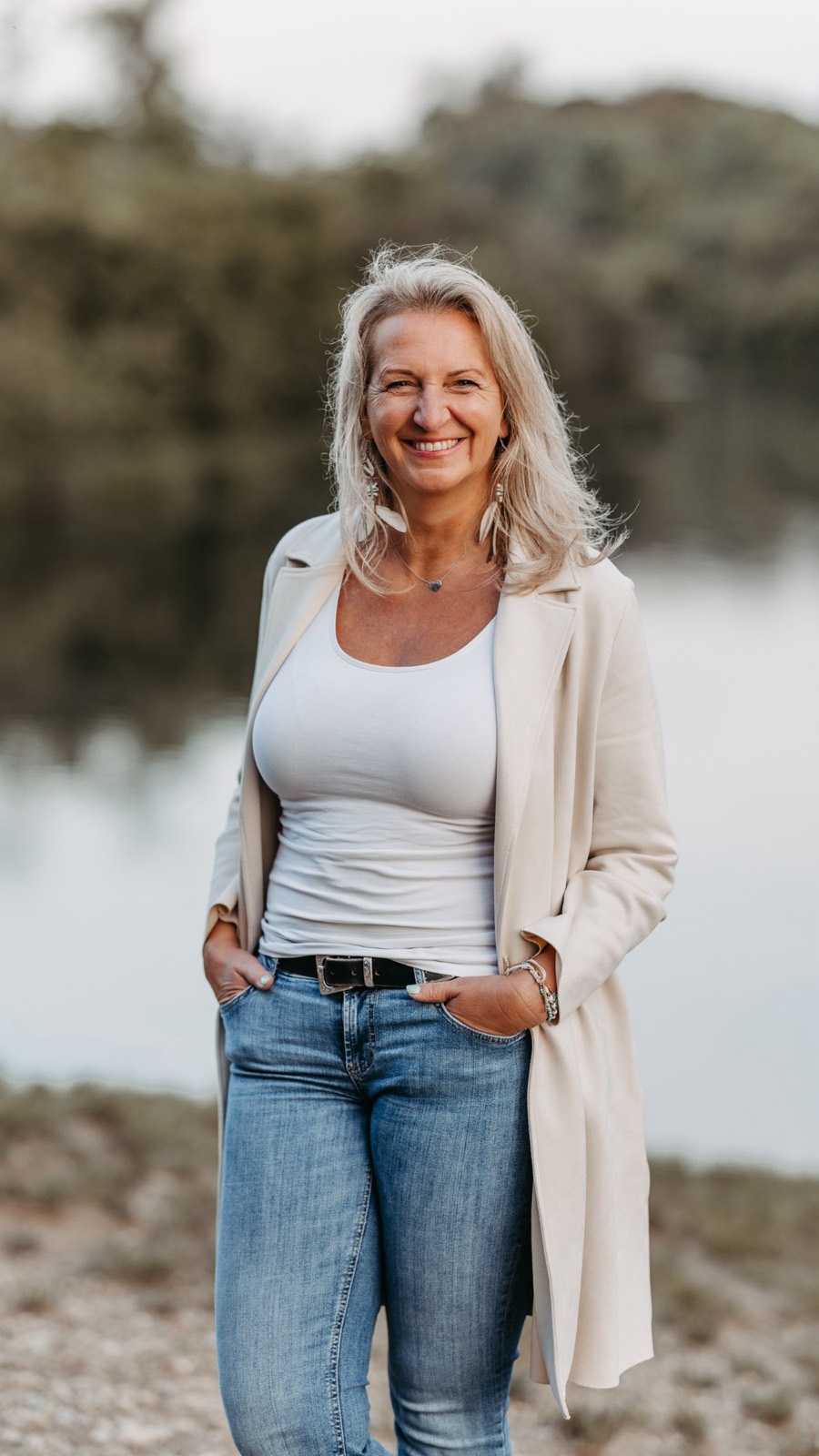 Maria Peischl im hellen Mantel am See