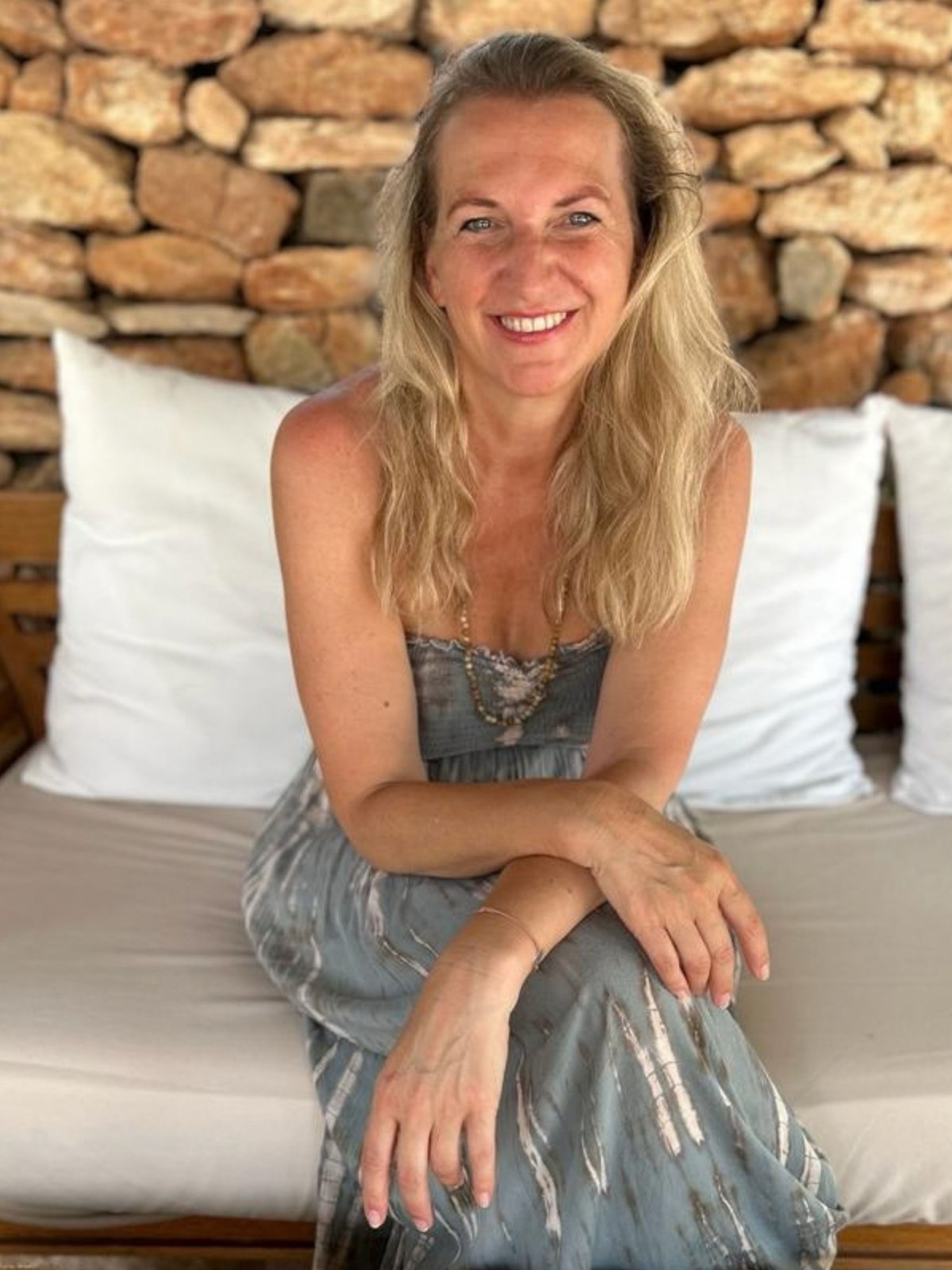 Maria Peischl vor einer sonnigen Natursteinmauer